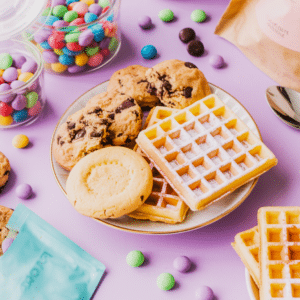 Una imagen de platos llenos de dulces, caramelos, galletas, gofres y galletas con chispas de chocolate.